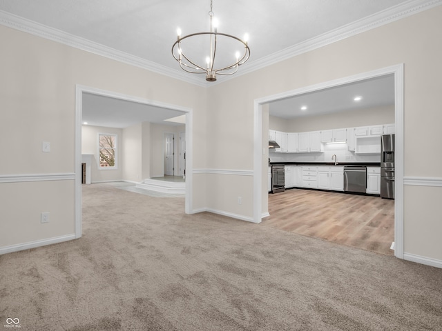 unfurnished dining area featuring crown molding, sink, light colored carpet, and a notable chandelier