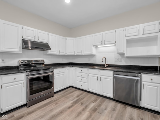 kitchen featuring tasteful backsplash, white cabinetry, sink, light hardwood / wood-style floors, and stainless steel appliances