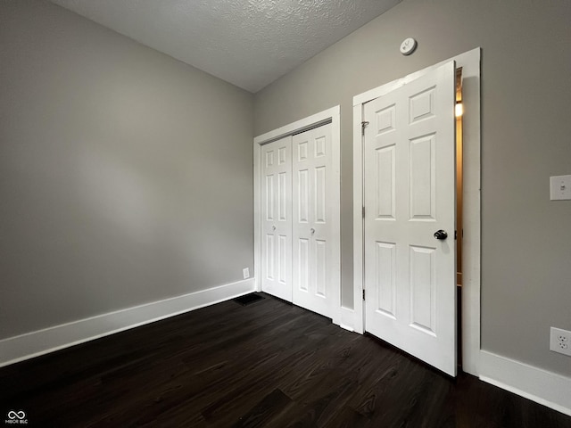 unfurnished bedroom featuring dark wood-type flooring, a textured ceiling, and a closet