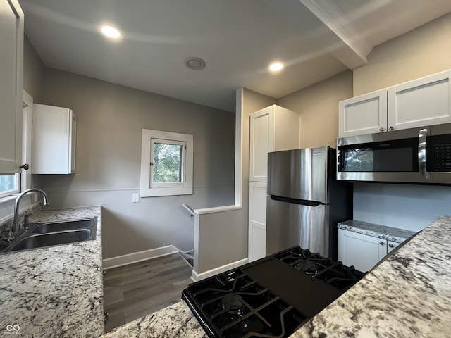 kitchen with sink, stainless steel appliances, dark hardwood / wood-style floors, light stone counters, and white cabinets