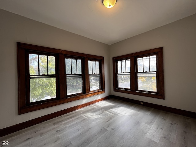 empty room with vaulted ceiling and light wood-type flooring