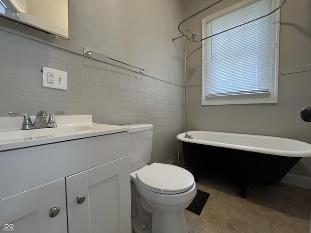 bathroom with vanity, tile walls, a bathtub, and toilet