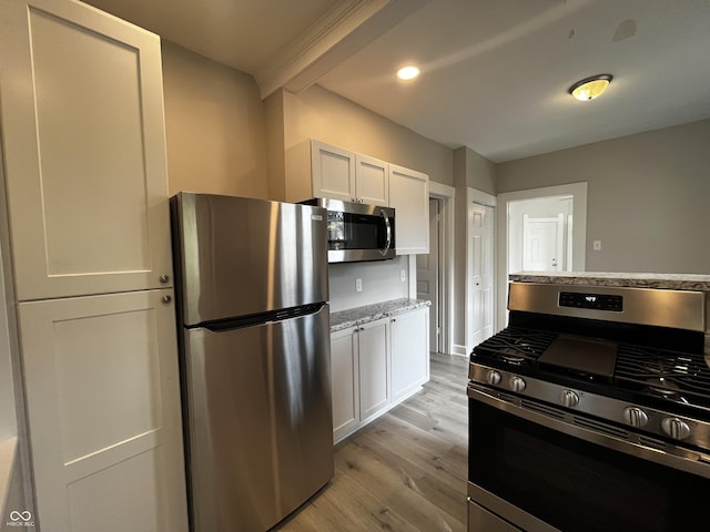 kitchen with light stone counters, stainless steel appliances, light hardwood / wood-style floors, and white cabinets