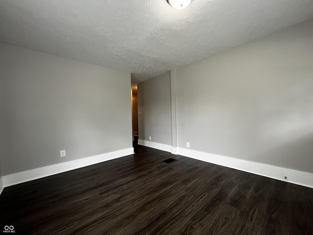 unfurnished room featuring dark wood-type flooring and a textured ceiling