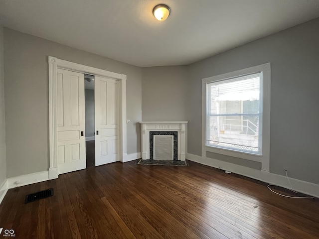 unfurnished living room with a high end fireplace and dark hardwood / wood-style floors