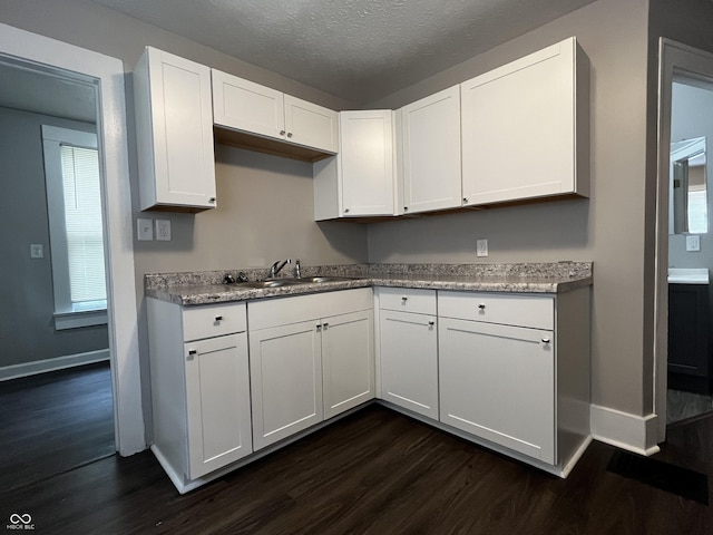 kitchen with dark hardwood / wood-style flooring, sink, a textured ceiling, and white cabinets