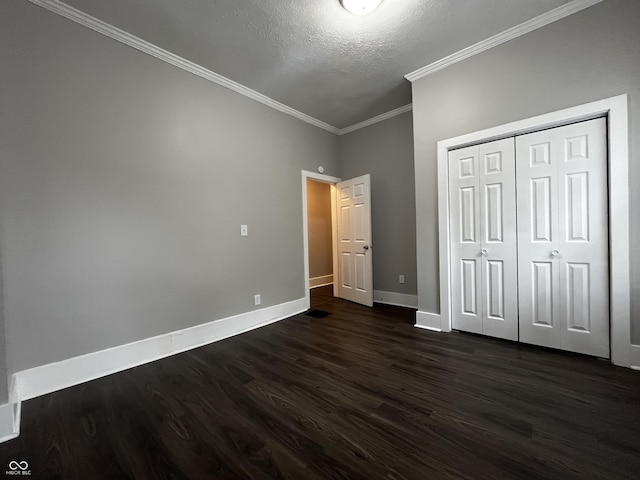 unfurnished bedroom with crown molding, dark hardwood / wood-style floors, a textured ceiling, and a closet