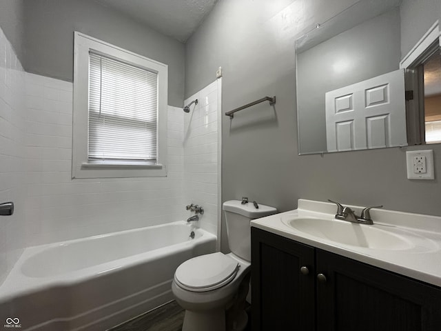 full bathroom with tiled shower / bath combo, vanity, hardwood / wood-style floors, and toilet