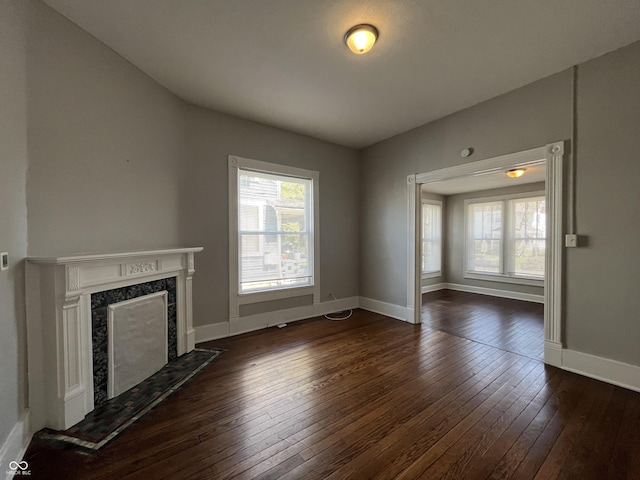 unfurnished living room featuring a premium fireplace and dark hardwood / wood-style flooring