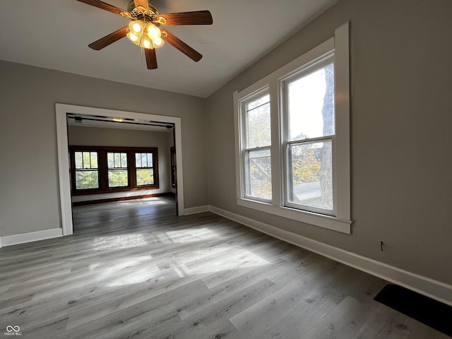 unfurnished room featuring a healthy amount of sunlight, ceiling fan, and light hardwood / wood-style flooring