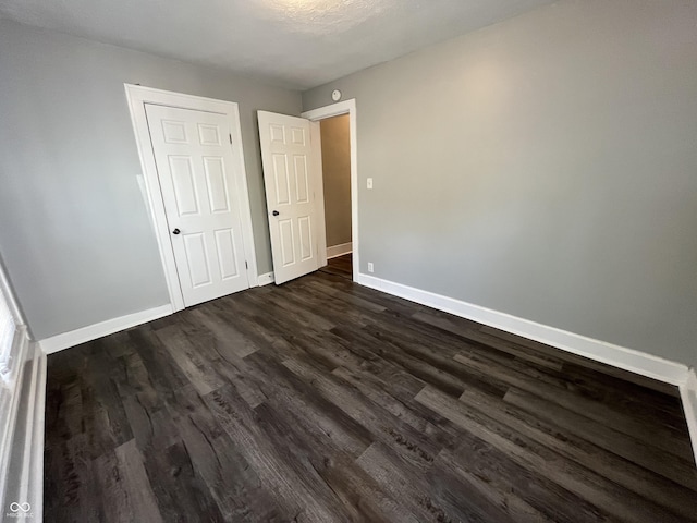 unfurnished bedroom with dark wood-type flooring