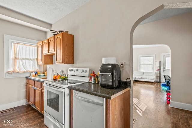 kitchen featuring white appliances, dark hardwood / wood-style floors, and a textured ceiling