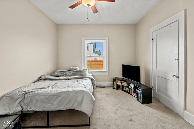 bedroom featuring ceiling fan, light carpet, and a textured ceiling