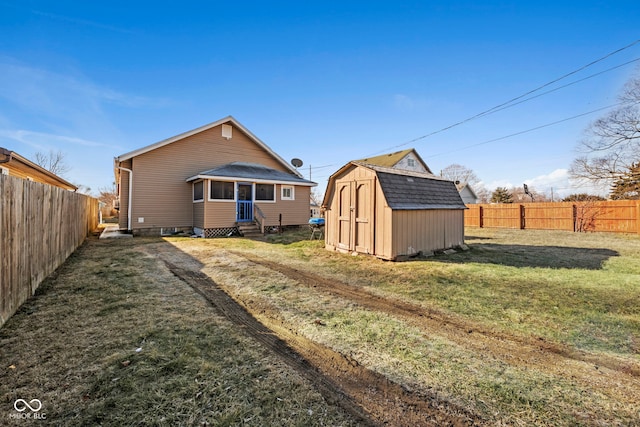 rear view of house with a storage unit and a lawn