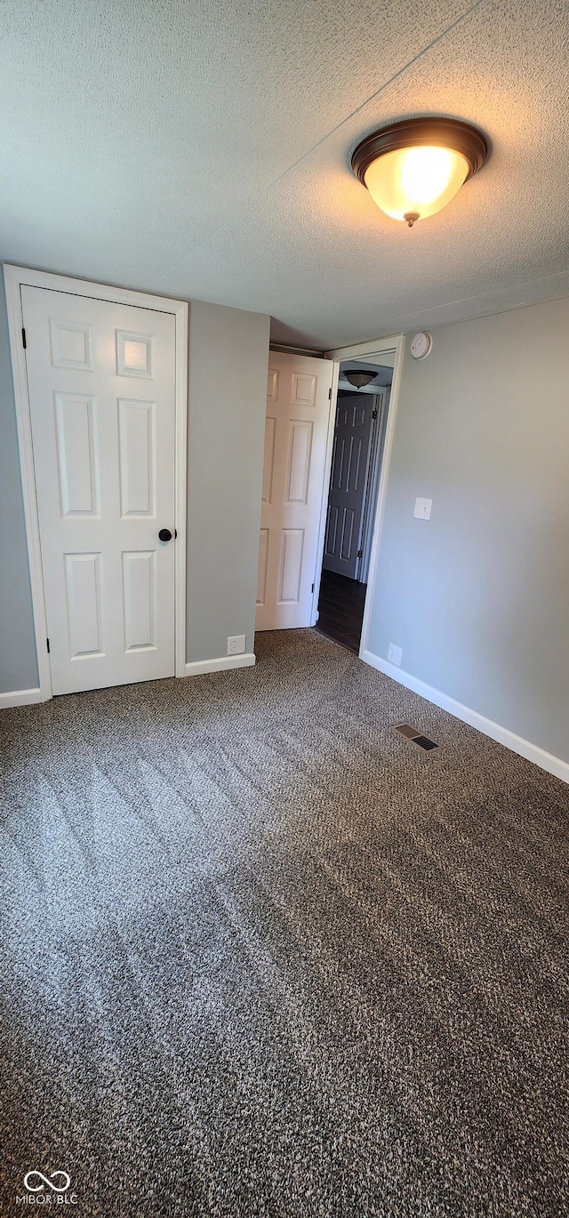 unfurnished bedroom featuring dark carpet and a textured ceiling