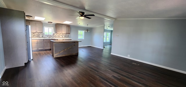 kitchen featuring crown molding, dark wood-type flooring, backsplash, a center island, and decorative light fixtures