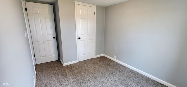 unfurnished bedroom with dark carpet and a closet