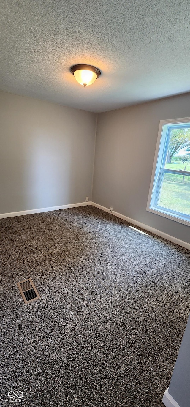 carpeted empty room with a textured ceiling