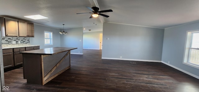 kitchen featuring crown molding, dark hardwood / wood-style flooring, a kitchen island, pendant lighting, and decorative backsplash