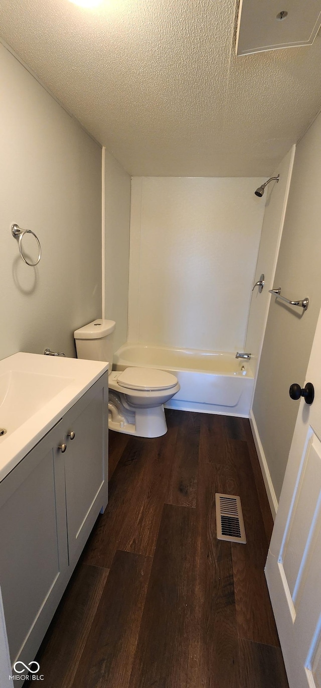 full bathroom featuring hardwood / wood-style flooring, vanity, toilet, and a textured ceiling