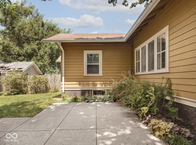 view of property exterior featuring a lawn, a patio, and fence