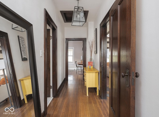 corridor with baseboards and dark wood-style flooring