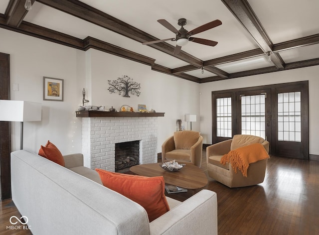 living area featuring beam ceiling, dark wood-type flooring, a ceiling fan, coffered ceiling, and a brick fireplace