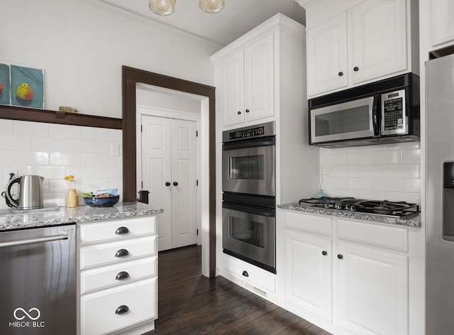 kitchen featuring light stone counters, stainless steel appliances, dark wood-type flooring, white cabinetry, and backsplash