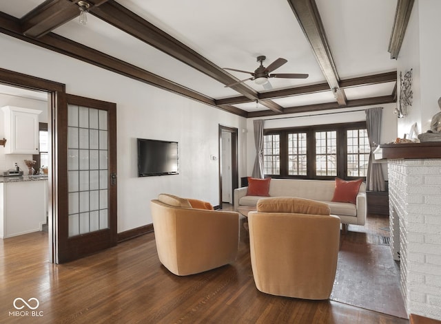 living room with ceiling fan, dark wood finished floors, beam ceiling, a fireplace, and coffered ceiling