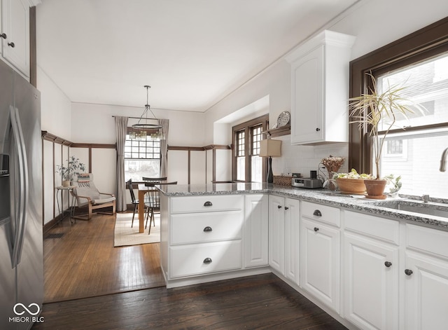 kitchen featuring dark wood finished floors, a peninsula, stainless steel refrigerator with ice dispenser, and a wealth of natural light