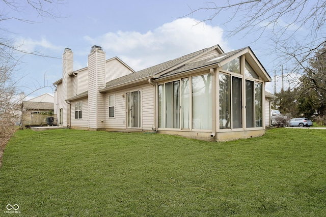 rear view of house featuring a lawn and a sunroom