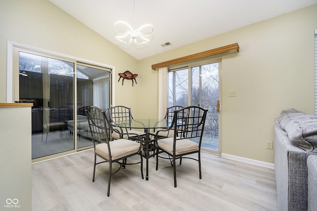 dining room featuring vaulted ceiling, a notable chandelier, and light hardwood / wood-style flooring