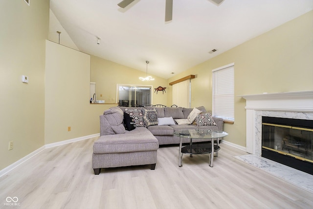 living room featuring lofted ceiling, a fireplace, ceiling fan, and light wood-type flooring