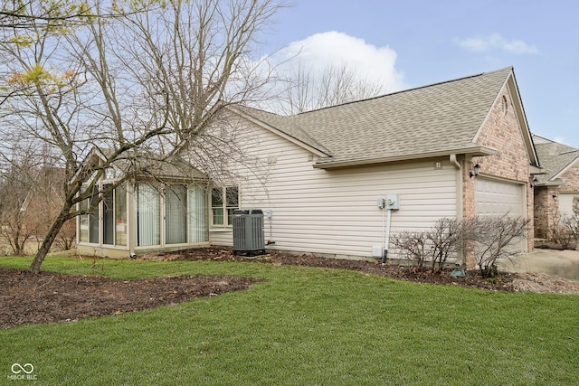 view of side of home featuring central AC unit, a garage, a lawn, and a sunroom