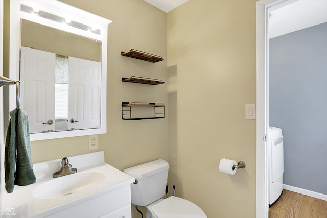 bathroom with hardwood / wood-style flooring, vanity, washer / clothes dryer, and toilet