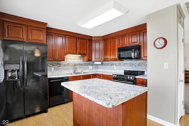 kitchen with sink, tasteful backsplash, light wood-type flooring, a kitchen island, and black appliances