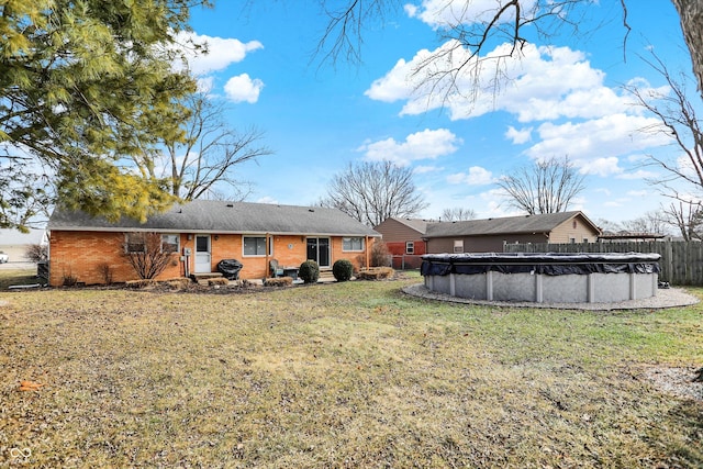 rear view of property featuring a covered pool and a lawn