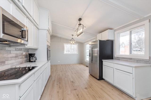 kitchen with stainless steel appliances, lofted ceiling, light countertops, and white cabinetry