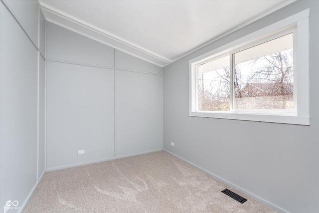 spare room with lofted ceiling, carpet, and visible vents