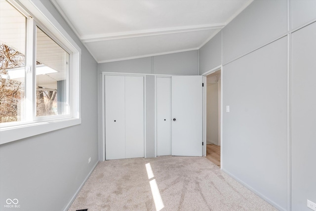 unfurnished bedroom with lofted ceiling with beams and carpet