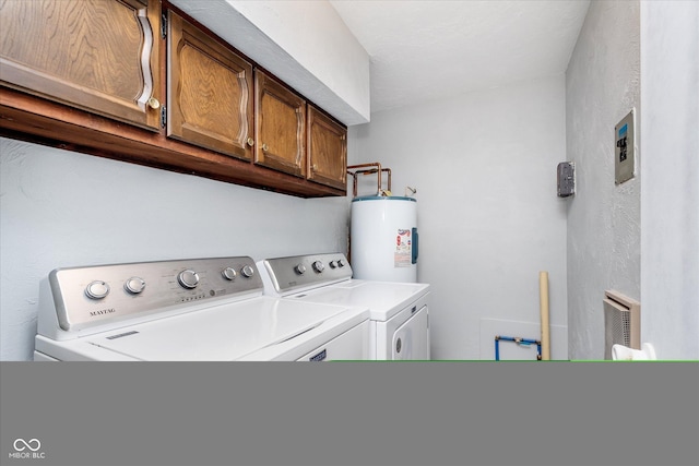 washroom featuring cabinet space, water heater, and washing machine and clothes dryer