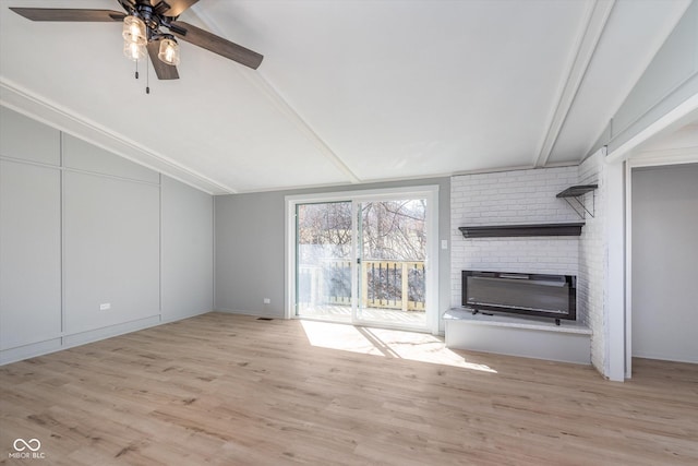 unfurnished living room featuring light wood-style floors, a fireplace, lofted ceiling with beams, and a ceiling fan