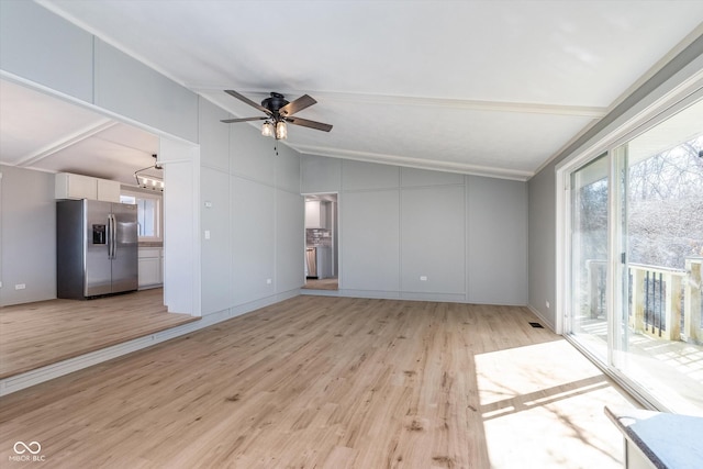 unfurnished living room with light wood-style floors, lofted ceiling, and a decorative wall