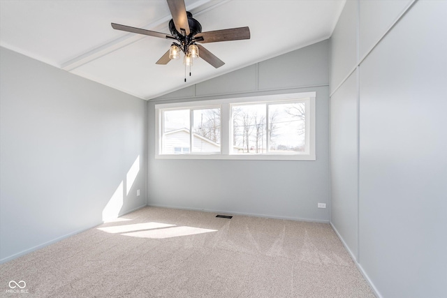 carpeted empty room featuring a ceiling fan, visible vents, and vaulted ceiling