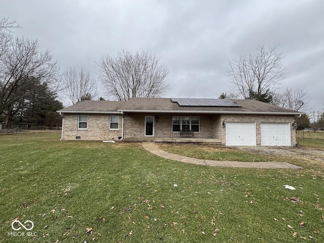 view of front of home with a garage, a front yard, and solar panels