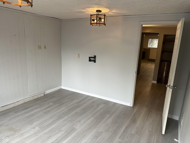 unfurnished dining area featuring a textured ceiling, wood finished floors, and baseboards