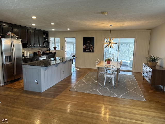 kitchen featuring dark wood-style floors, black appliances, a textured ceiling, and a kitchen breakfast bar