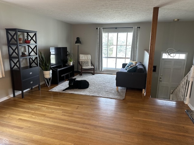 living room featuring a textured ceiling, baseboards, and light wood-type flooring
