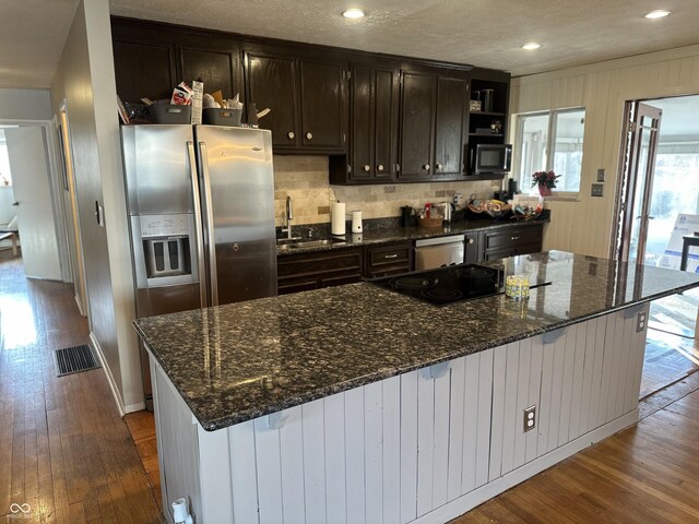 kitchen featuring dark wood finished floors, stainless steel appliances, backsplash, and a sink