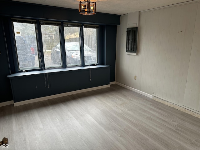 spare room with a textured ceiling, a chandelier, light wood-type flooring, and baseboards